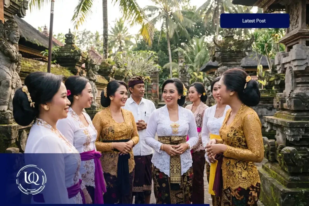 A cheerful group of locals in traditional attire talking and exchanging balinese words with each other in a beautiful stone temple courtyard.